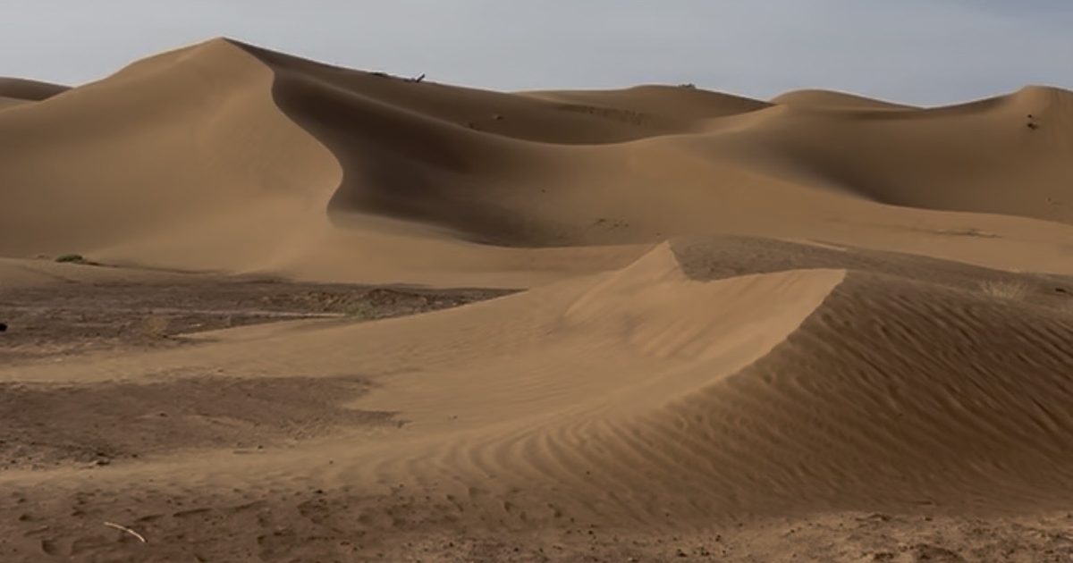 Grandes dunes de sable du désert marocain sous un ciel nuageux