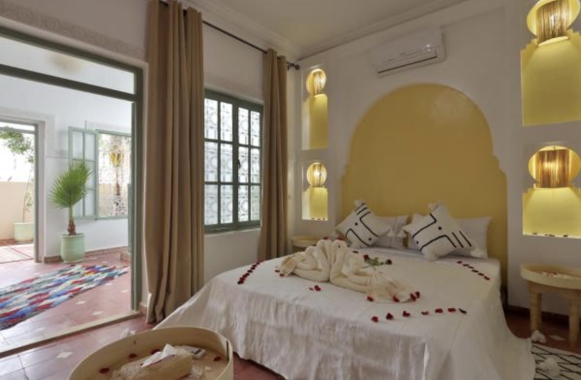 Chambre du riad : lit blanc ouvert sur la terrasse